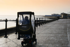 Elderly person using the Scooterpac Universal Foldaway mobility scooter Canopy. automated Rain protection