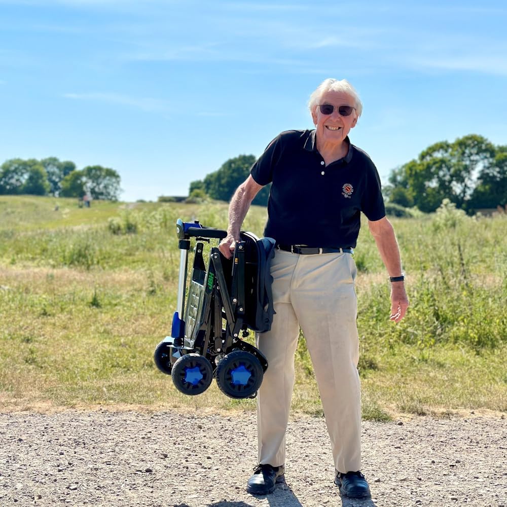 Folded mobility scooter lifted up by elderly man