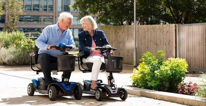 Two lightweight mobility scooters in used outside 