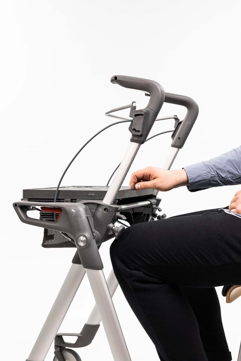 man sitting down at the ToPro Hestia Rollator moving the tray