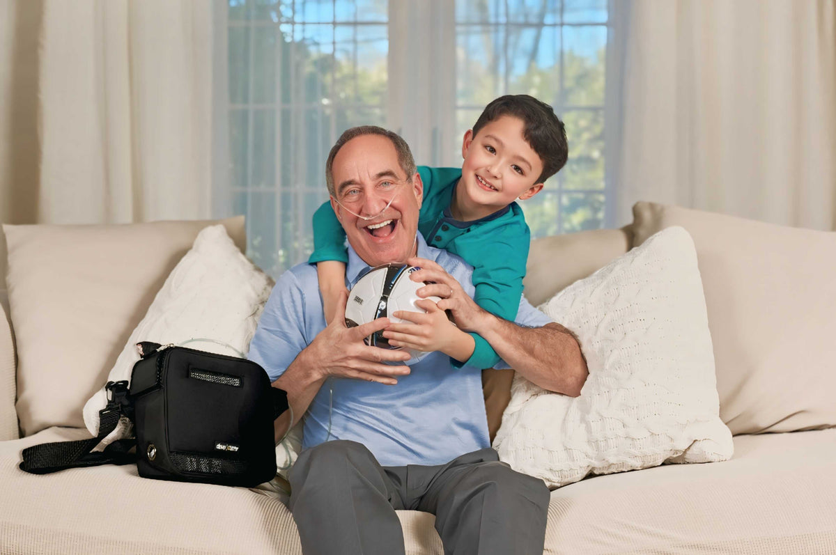 Drive Devilbiss iGo2 Portable Oxygen Concentrator in use as user plays with his grandson