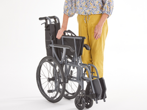 Woman folding the Motion Healthcare Magnelite transit and self propelled,, Lightweight, Folding Wheelchair, Manual and Self Propelled