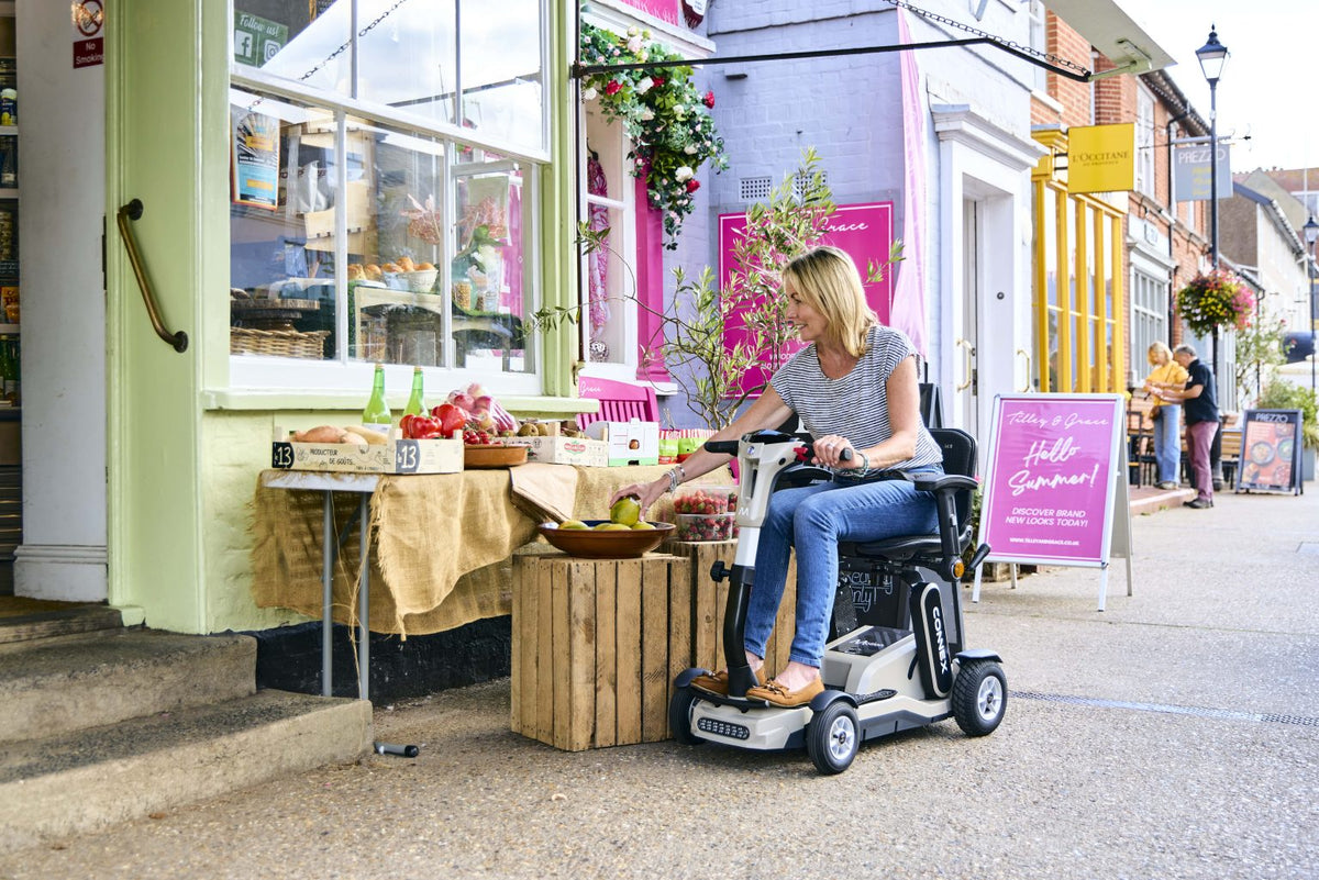 Motion Healthcare Connex Automatic Folding Mobility Scooter in colour sand in use outside