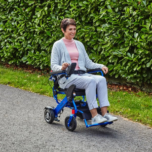 woman using Motion Healthcare Foldalite Pro Folding Electric Wheelchair Blue powerchair