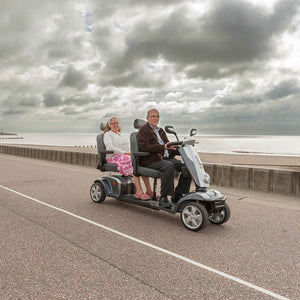 Two elderly people riding Scooterpac Tandem 2 Seat Mobility Scooter. Two-Person Mobility Solution