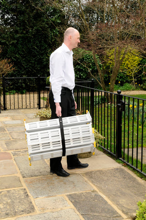 man carrying the Roll-a-ramp portable and foldable disabled wheelchair ramp