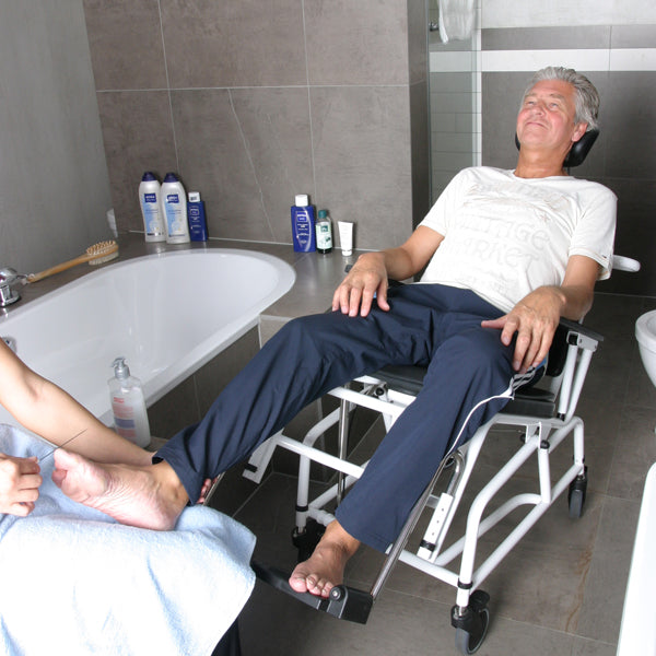 Direct Healthcare Group Combi TIlt Shower Commode Shower Chair Tilted front view with patient  in bathroom 