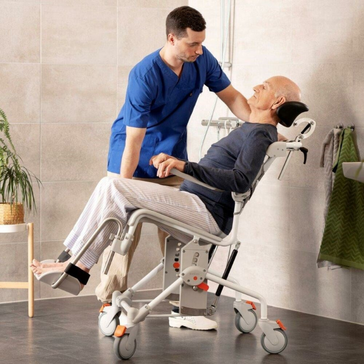 Etac | Swift Mobil Tilt-2 Comfortable and Safe Shower Commode Chair for Carer and User Unique Tilt Function man helping patient