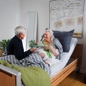 Invacare | Invacare Etude Plus Low Care Bed Safety, Durability, and Community Care Convenience man and woman sitting on bed