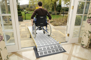 man using the Roll-a-ramp portable and foldable disabled wheelchair ramp to exit home into back yard in his wheelchair