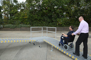 man pushing a wheelchair up the Roll-a-ramp portable and foldable disabled wheelchair ramp with patform