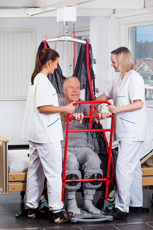 Two carers assisting patient in a sitting position with Direct Healthcare Group SafeHandlingSheet laid Horizontal Sling and Transfer Aid attached to ceiling hoist