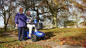 Man riding Blue Scooterpac Ignite 8mph Electric Mobility Scooter 40 Mile Range tiller and control panel